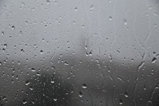 October 19, 2026, Marseille, France: A view of raindrops and streaks of water trickling down a clear glass pane against a dreary background on a rainy day.