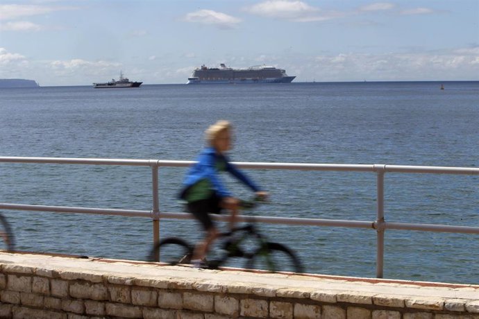 Archivo - Una mujer, con un crucero en la bahía de Palma, pasea en bicicleta.