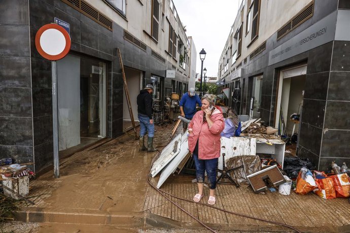 Diverses persones lleven el fang dels carrers mentre s'acumula el mobiliari que han hagut de traure a causa de les inundacions per les fortes pluges, a 19 d'octubre del 2026, a Els Poblets