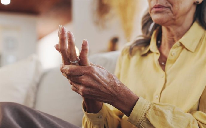 Archivo - Mujer madura, dolor de manos y artritis por inflamación de las articulaciones, problemas médicos y osteoporosis. Persona mayor, masaje de dedos y lesión muscular en casa con fibromialgia, riesgo de túnel carpiano