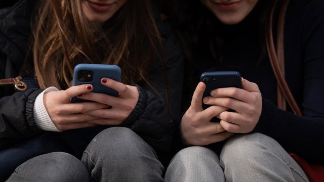 Archivo - Dos personas usan el teléfono móvil