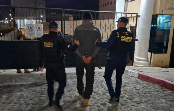 Dos miembros de la Policía Nacional Civil de Guatemala detienen a hombre en Quetzaltenango.