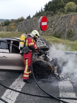 Un bombero trabaja en la extinción del fuego declarado en el coche