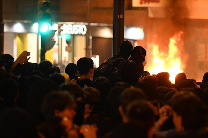 Jóvenes observan un contenedor ardiendo en los incidentes de Bilbao