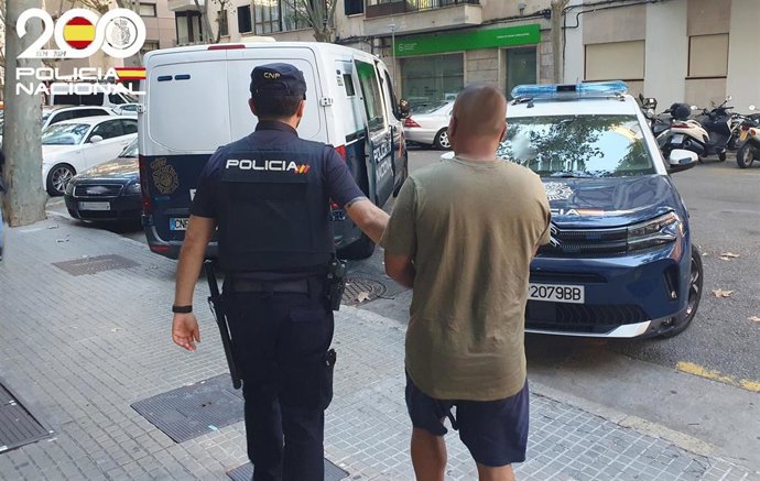 Un agente de la Policía Nacional traslada a un detenido en una calle de Palma.