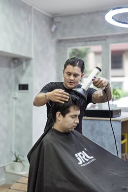 Juan secándole el pelo a un cliente.