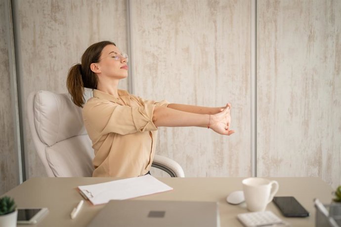 Archivo - Mujer haciendo ejercicio de estiramentos en el trabajo.