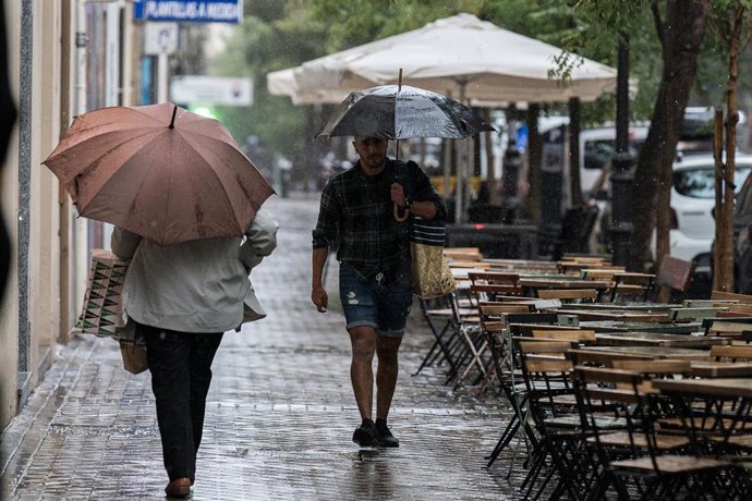 Archivo - Varias personas se resguardan de la lluvia con paraguas, a 3 de septiembre de 2023, en Madrid (España).